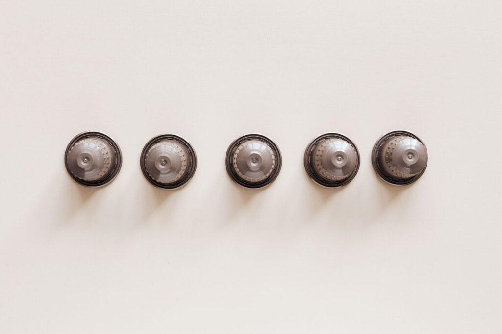 Top view of coffee blends in disposable coffee capsules for espresso machine on white background.